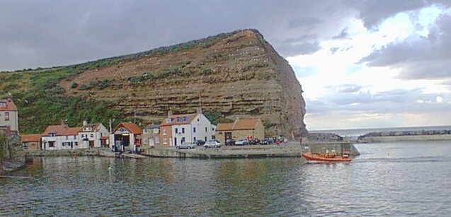 The Staithes Lifeboat, nearly home safe and sound with the Lifeboat Station and Cow Bar Nab in the background.
